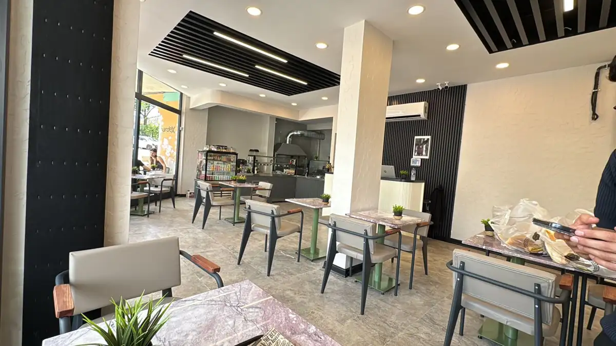 Be. Point Sandwich iç mekânı: mermer masalar ve yeşil sandalyeler